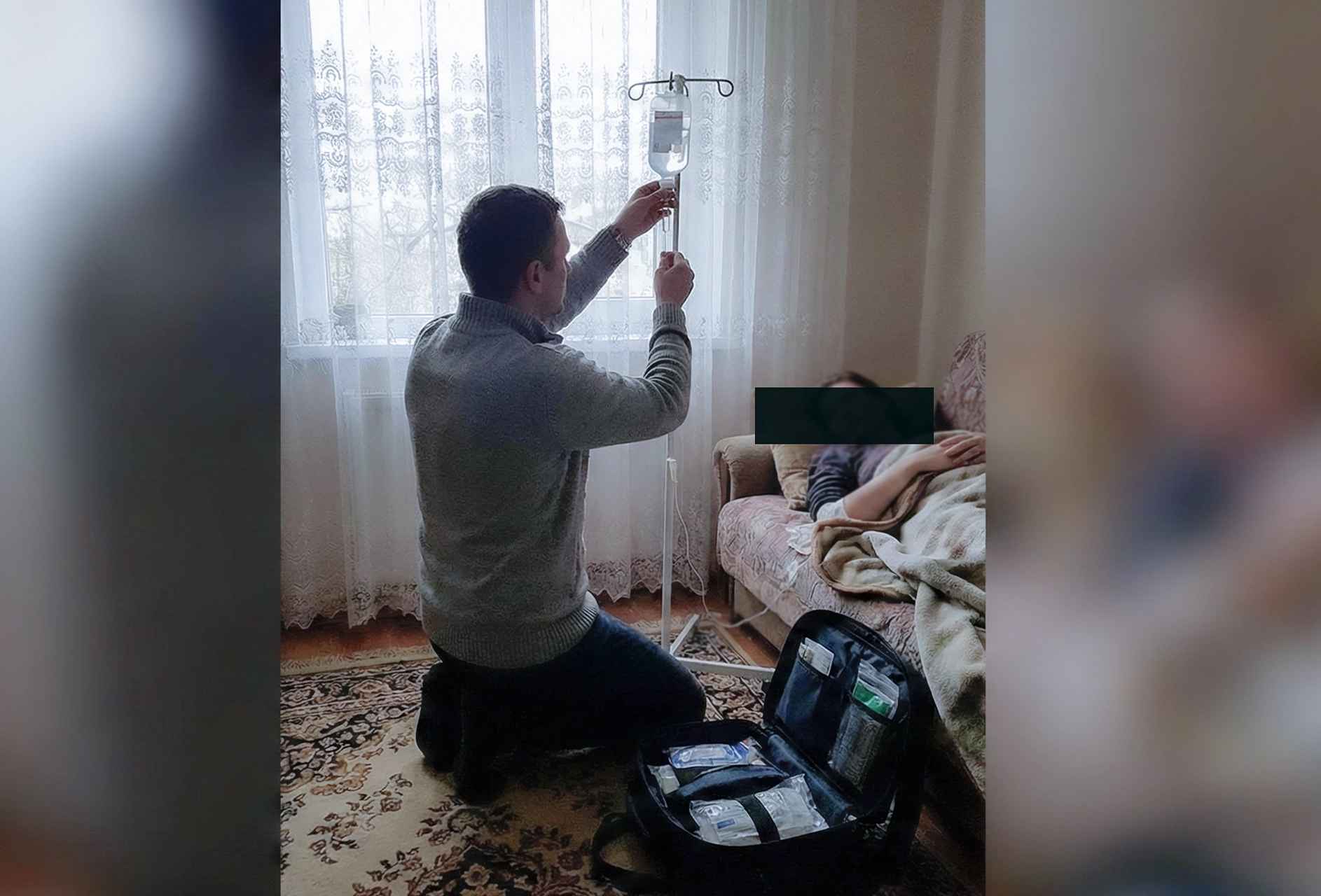 Врач на вызове на дом устанавливает капельницу и настраивает приборы для оказания помощи